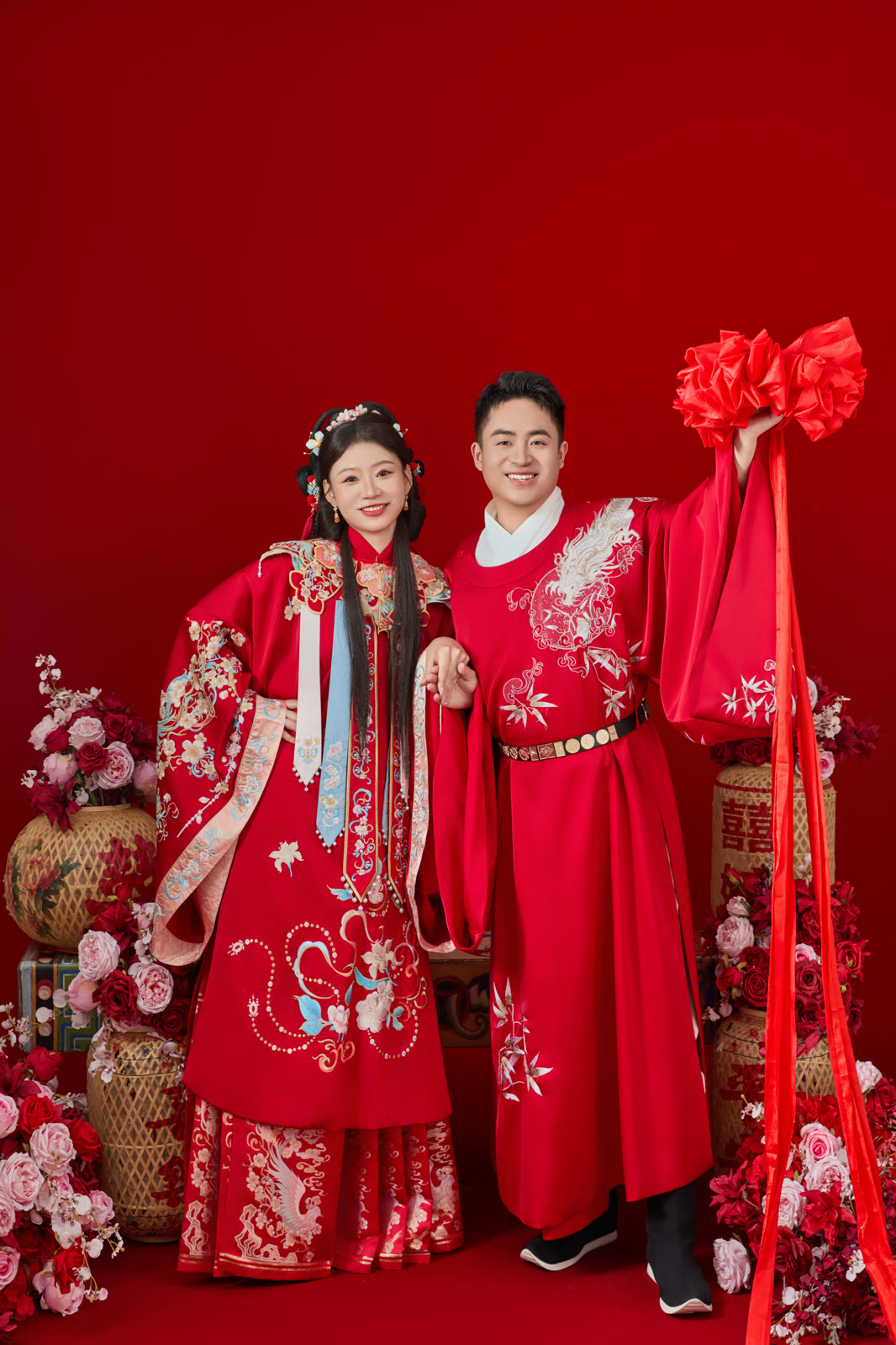 钱立勇与王若昕身着红色中式礼服，手持红绸花